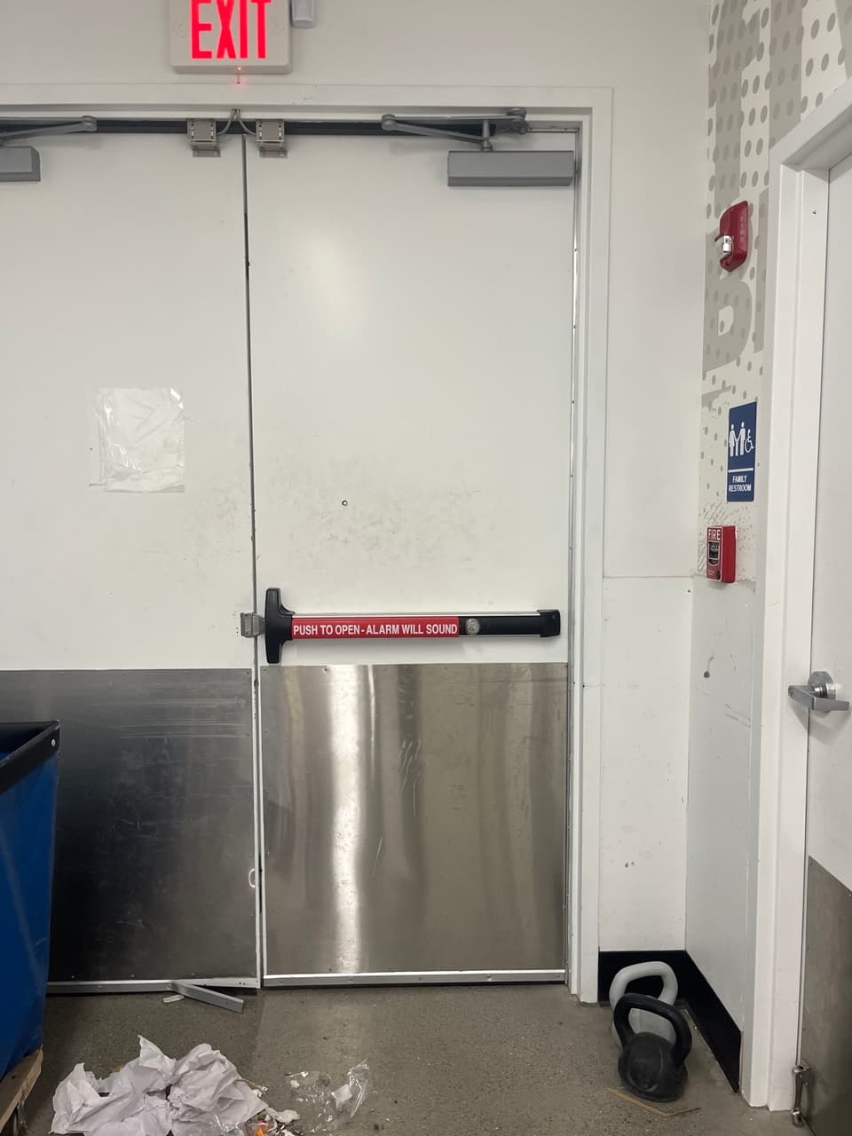 White emergency exit doors with a red push bar and a red exit sign above.