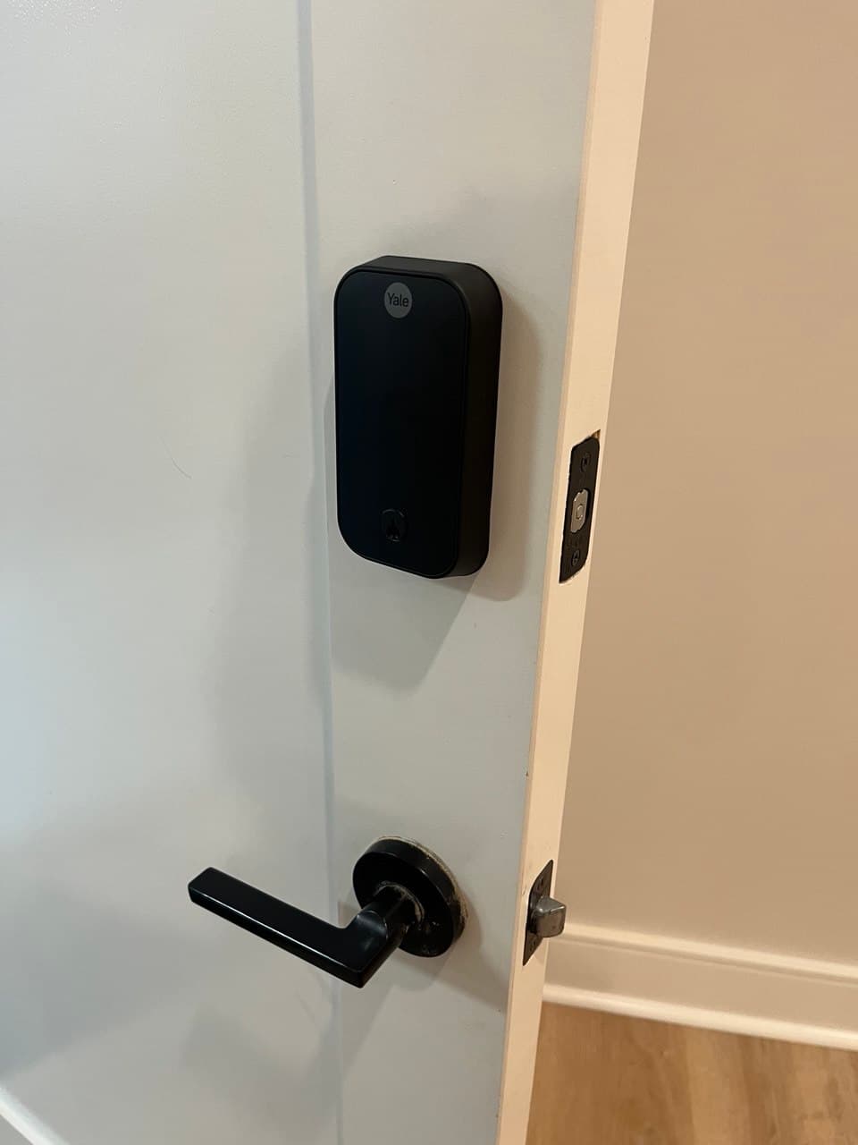 Black Yale smart lock and matching lever handle installed on a white interior door.